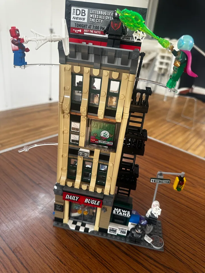 A tall Daily Bugle building model surrounded by superhero figures.