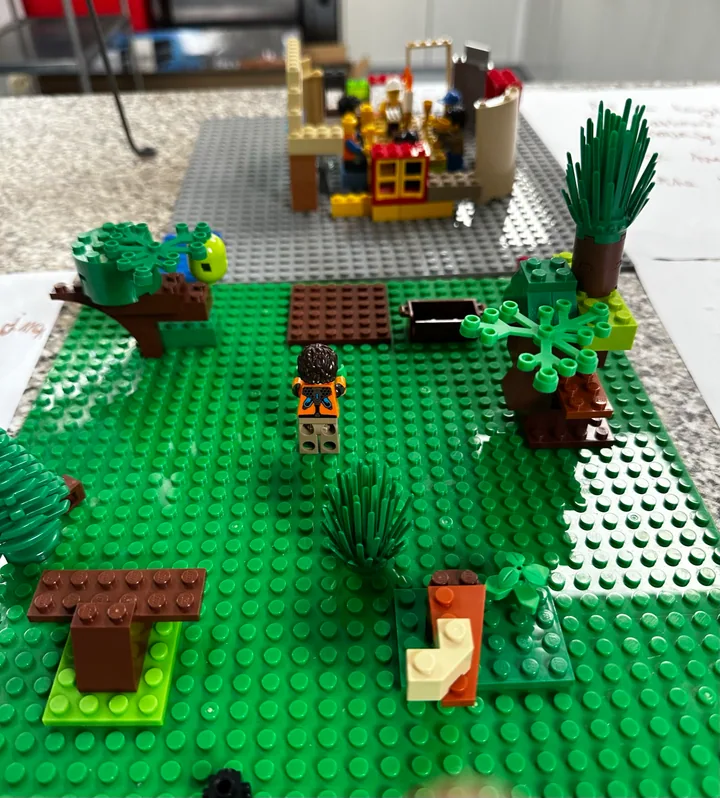 A miniature garden with benches, trees and a path leading towards a building.