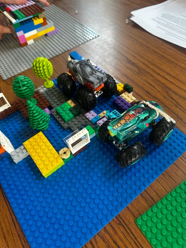 Two brick-built vehicles beside a small tree on a blue baseplate.