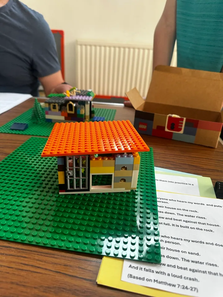 A small brick house with an orange roof beside a printed Bible story.
