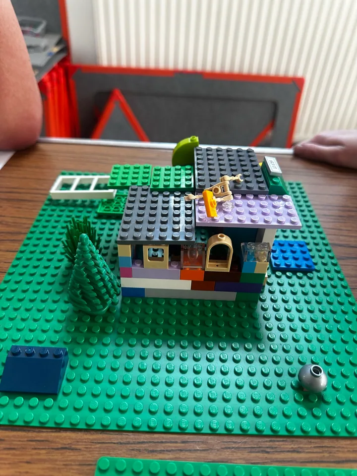 A colourful house with different roof sections on a green baseplate.