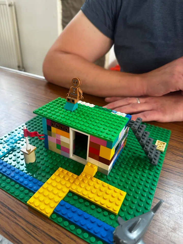 A multicoloured brick house with a green roof and a yellow path.